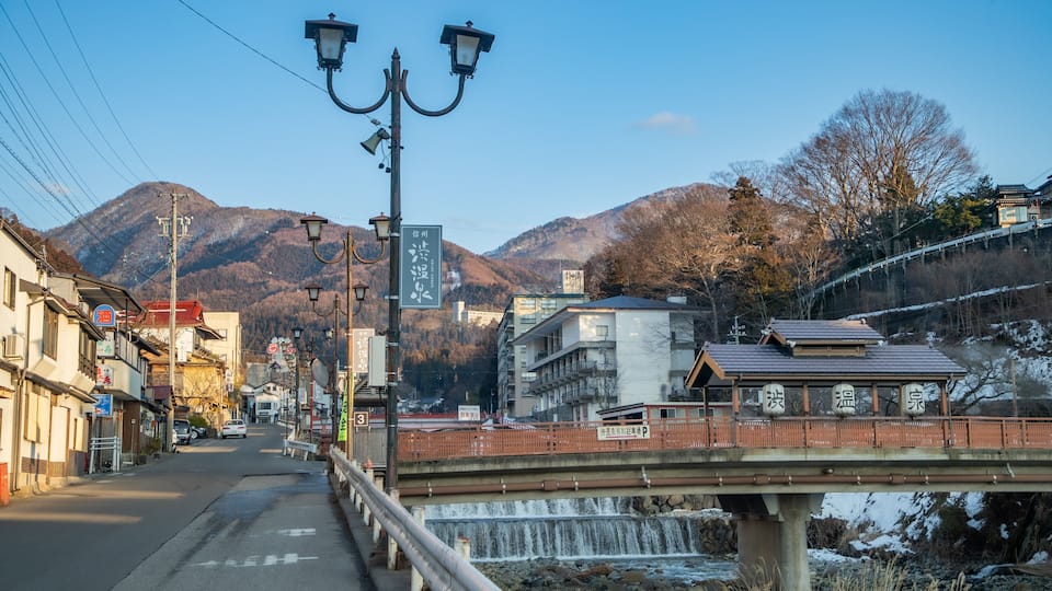 A bridge over a river with a mountainous backdrop.