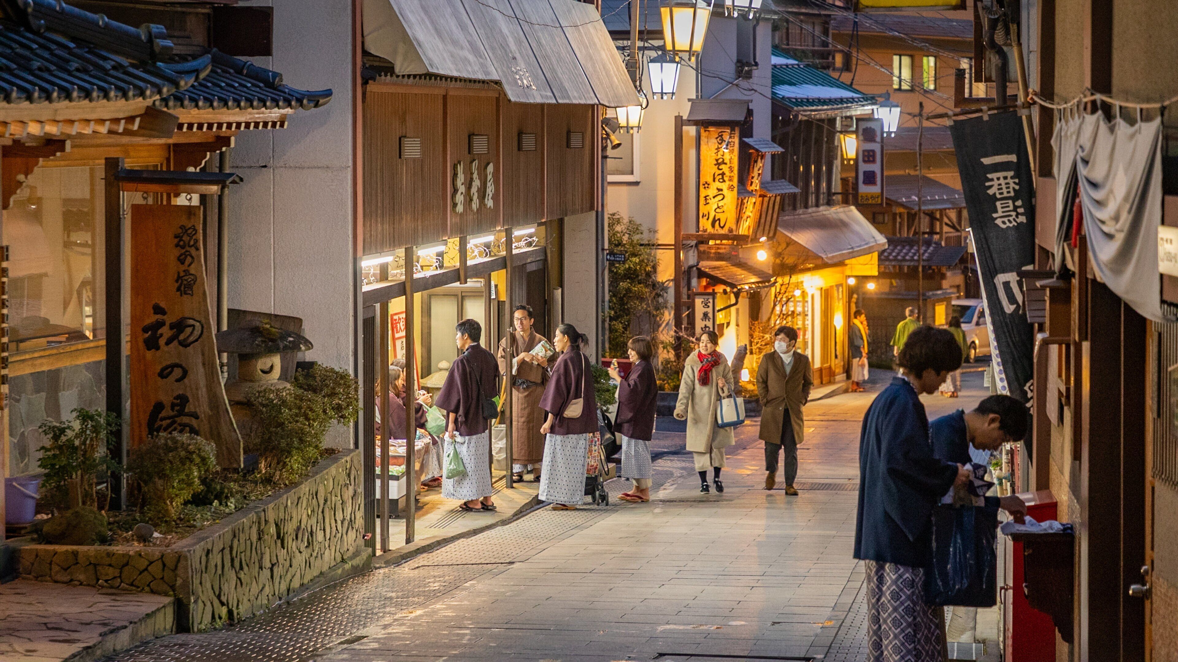 A bustling street in a traditional Japanese town with wooden buildings and lanterns.