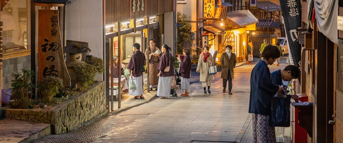 A bustling street in a traditional Japanese town with wooden buildings and lanterns.