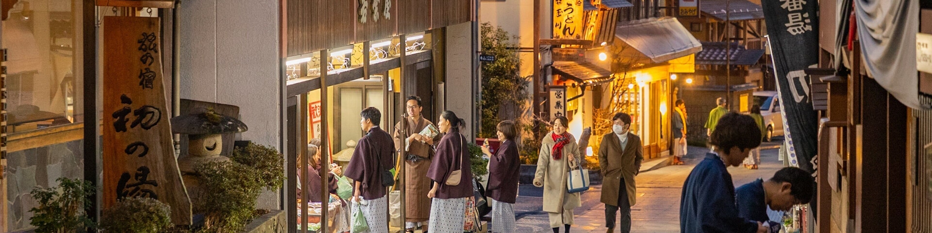 A bustling street in a traditional Japanese town with wooden buildings and lanterns.