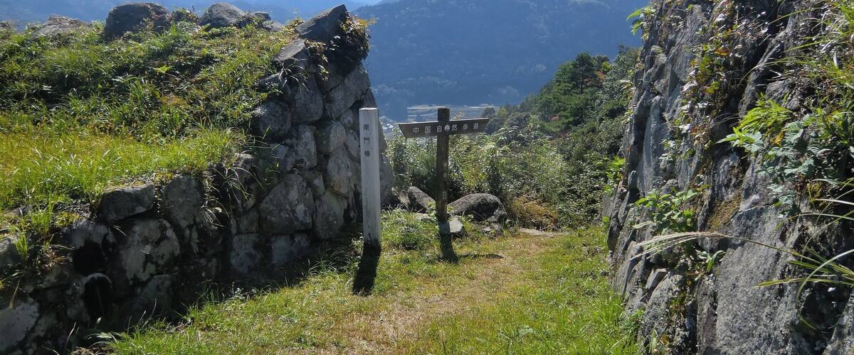 A stone pathway leading through a mountainous landscape with a signpost indicating directions.