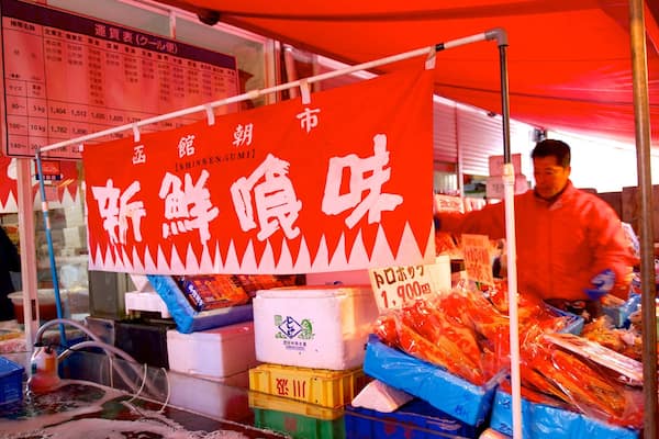 A street food stall with a red banner and various food items displayed.