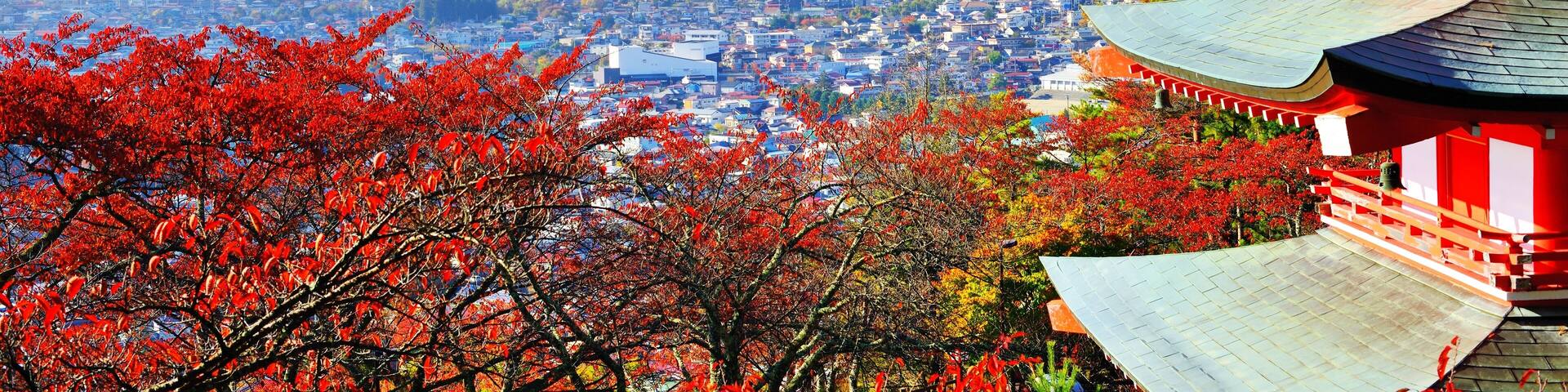 A snow-capped mountain, a traditional red building, and autumn foliage.