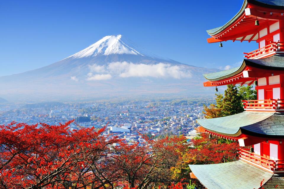 A snow-capped mountain, a traditional red building, and autumn foliage.