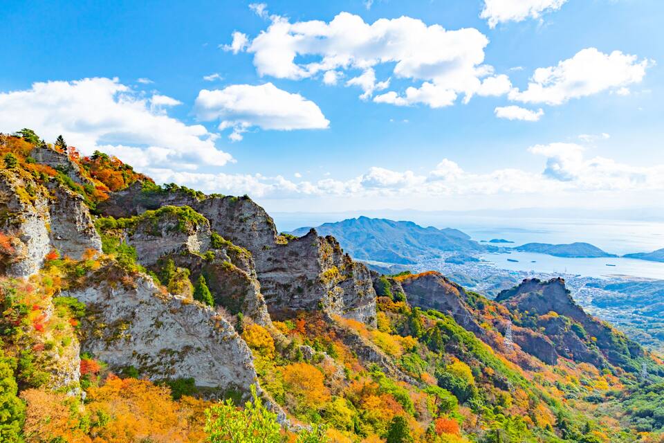 Un paisaje montañoso con riscos rocosos y follaje otoñal.
