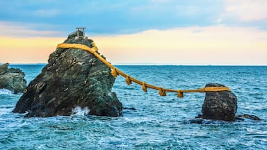 A rope tied around a rock formation with a wooden structure on top, surrounded by the ocean.