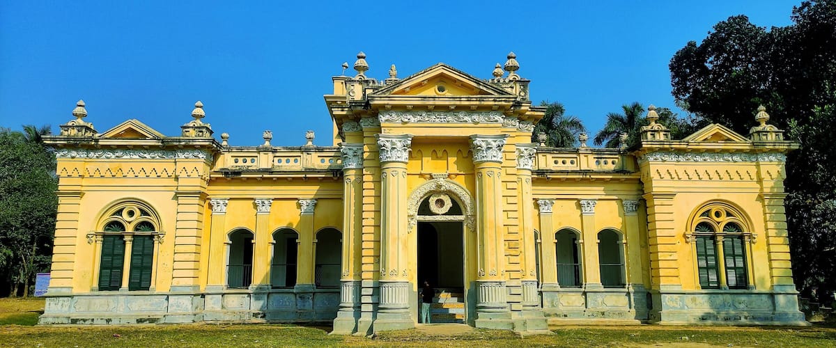 A yellow colonial-style building with ornate columns and arched windows.
