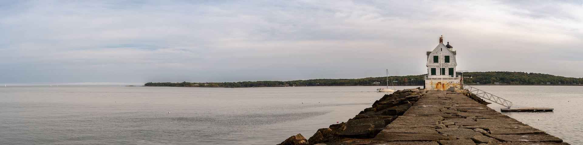 Long walkway leading to the Rockland Breakwater Lighthouse cutting through the harbor on the Gulf of Maine