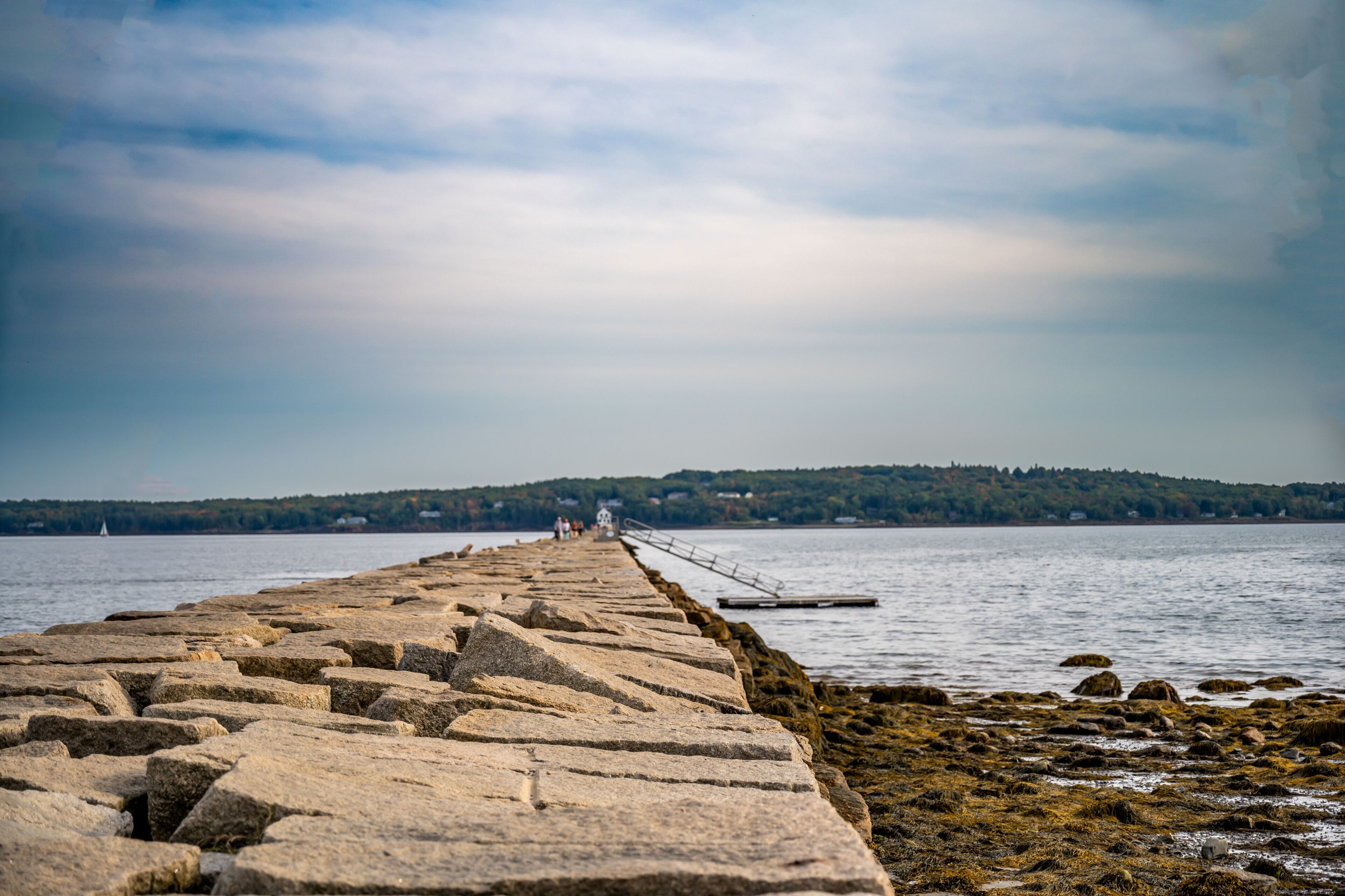Low level view of the uneven rock path leading out to the Rockland Breakwater Lighthouse cutting through the harbor on the Gulf of Maine