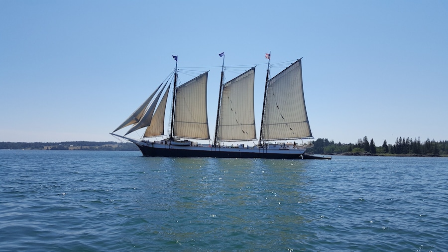 A sailboat with multiple sails on a calm body of water.