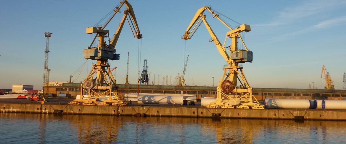 Two large cranes at a port with a calm water body in the foreground.