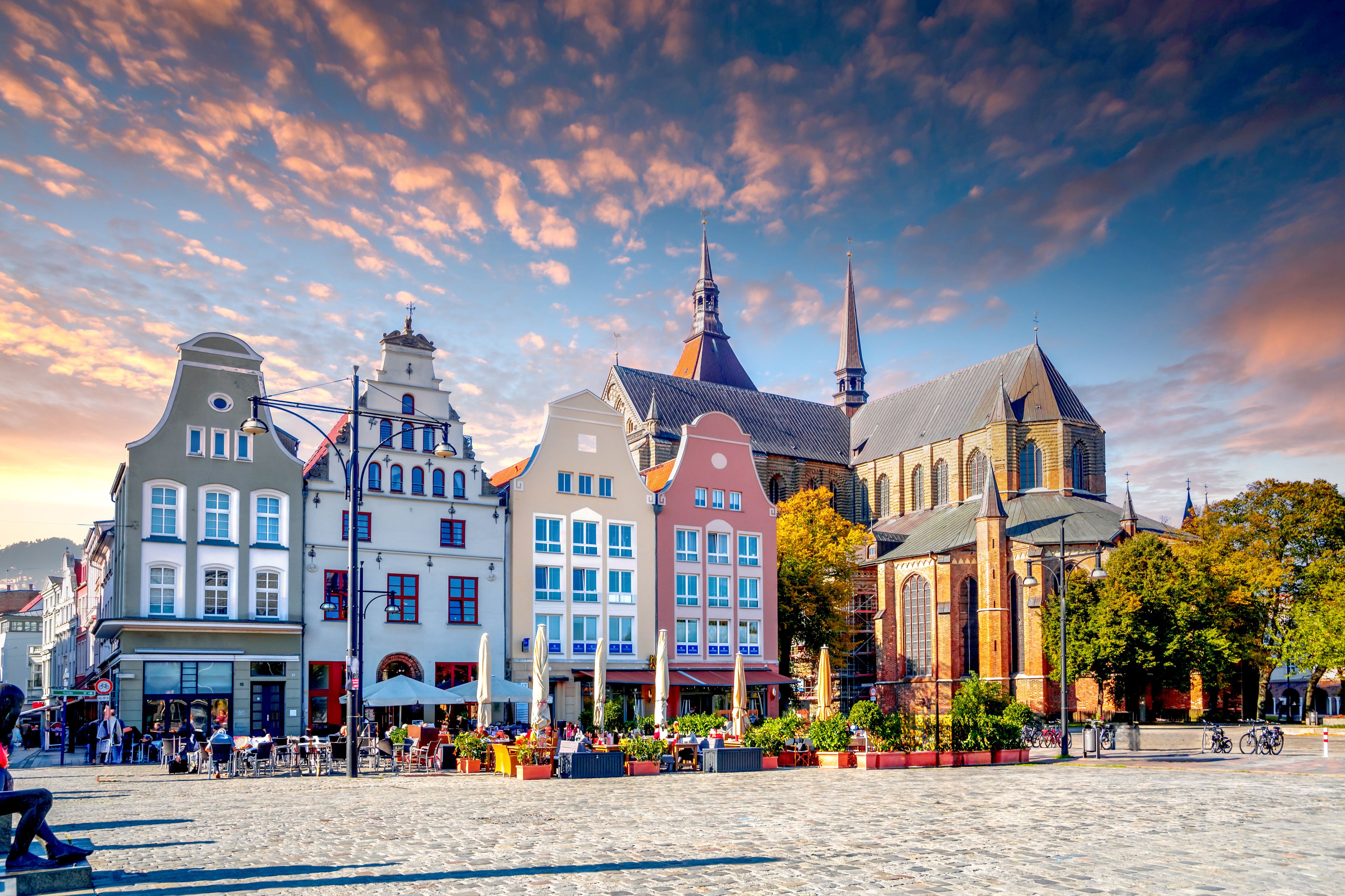 A historic European town square with colorful buildings, cobblestone streets, and a clear sky.