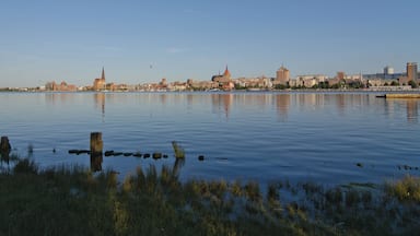 A calm river with a city skyline in the background, featuring a prominent church spire and modern buildings.