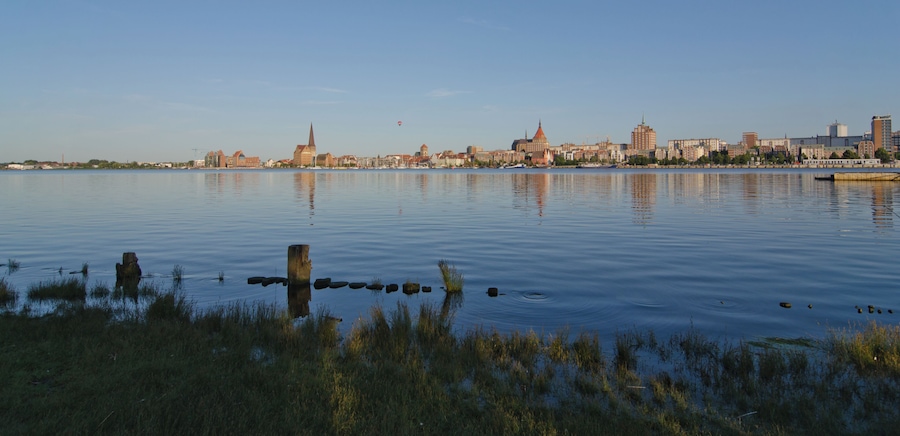 A calm river with a city skyline in the background, featuring a prominent church spire and modern buildings.