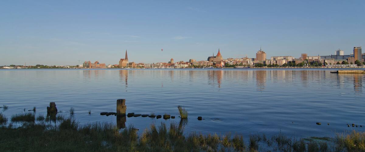 A calm river with a city skyline in the background, featuring a prominent church spire and modern buildings.
