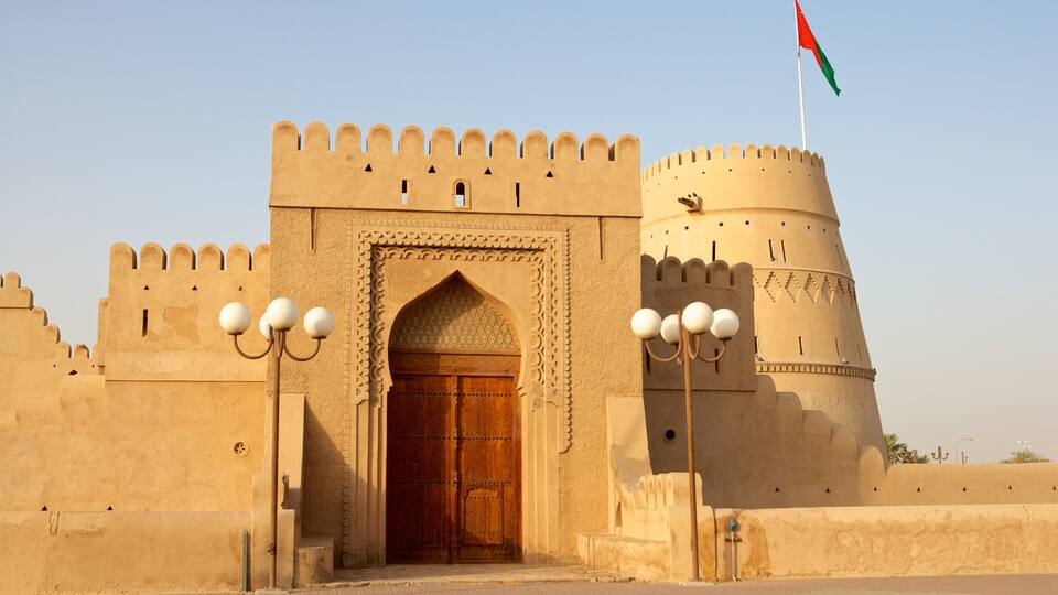 A historic fort with a large wooden door, a flag, and a round tower.