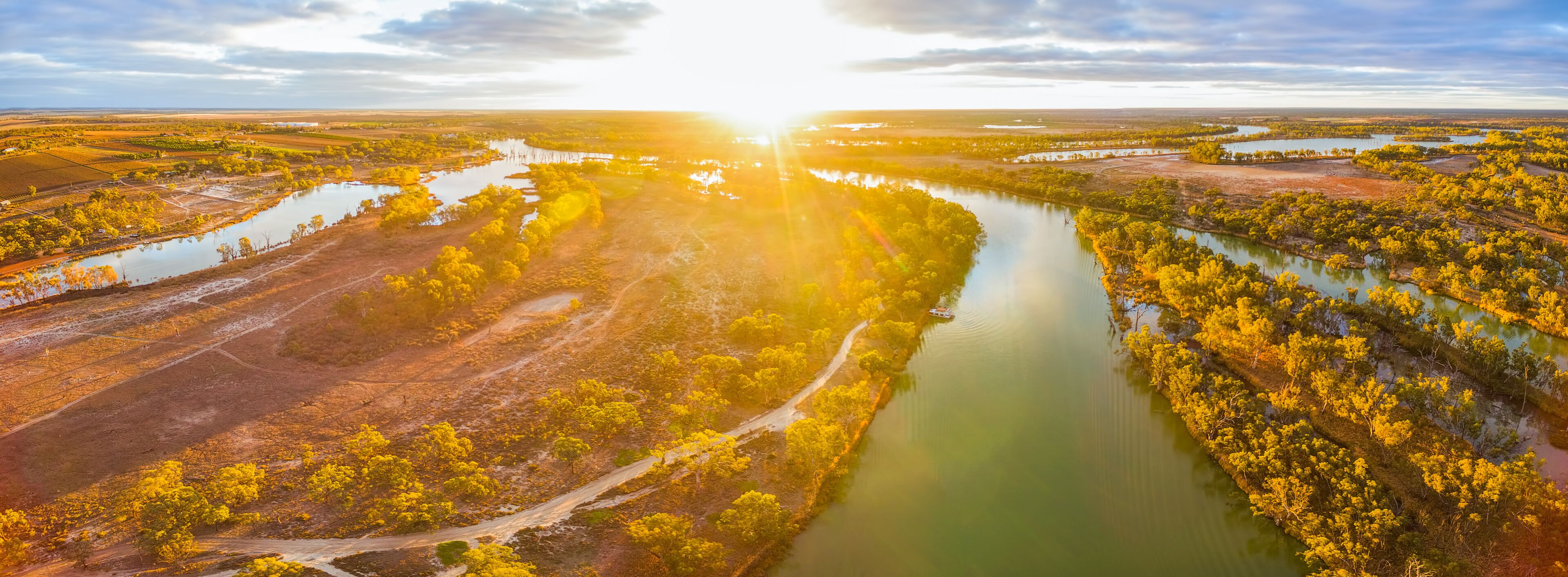 Aerial panorama of bright sun flare at sunset over Murray River in South Australia