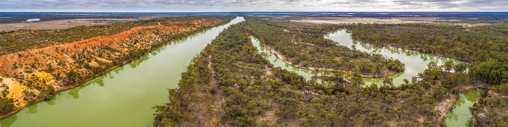 Wide aerial panorama of eroding sandstone cliffs over meandering Murray River in South Australia