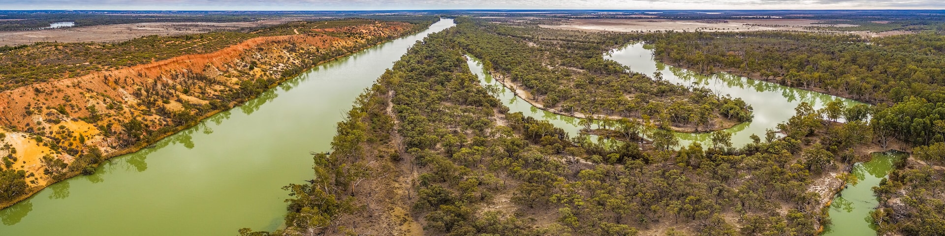 Wide aerial panorama of eroding sandstone cliffs over meandering Murray River in South Australia