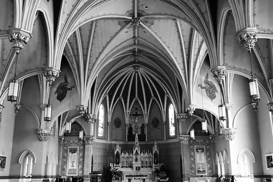 L’intérieur d’une église, avec une haute voûte, des fenêtres en arc de cercle et une nef centrale menant à l’autel.
