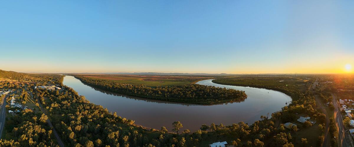 A river winding through a forested area with a small town on one side.