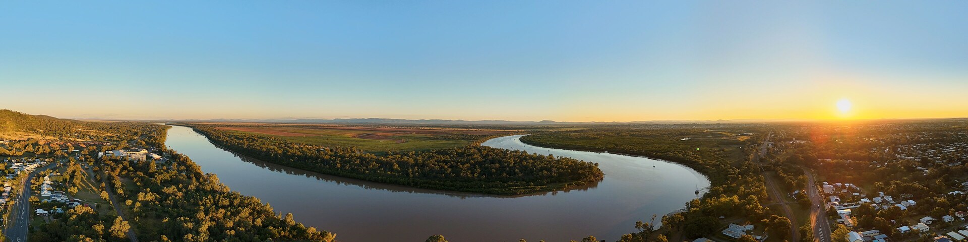 Un río serpentea por una zona boscosa con un pequeño pueblo a orillas.