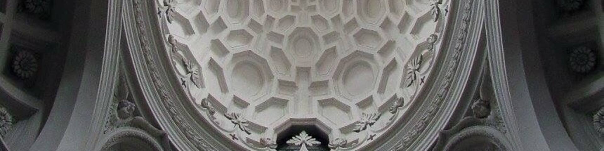 A detailed ceiling with a central emblem surrounded by a hexagonal pattern.