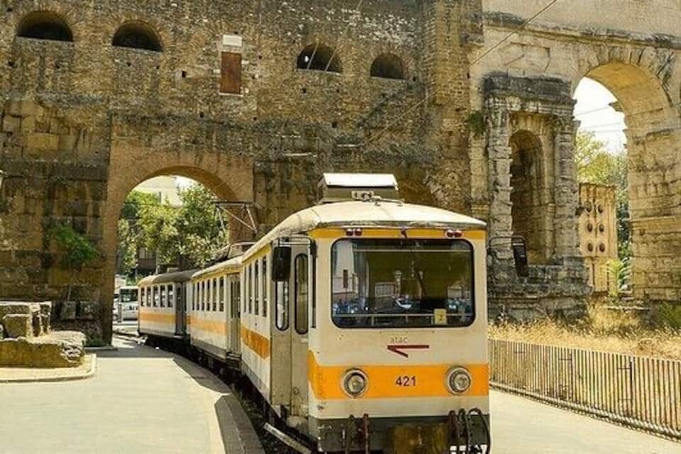 A train passing under an old stone bridge.
