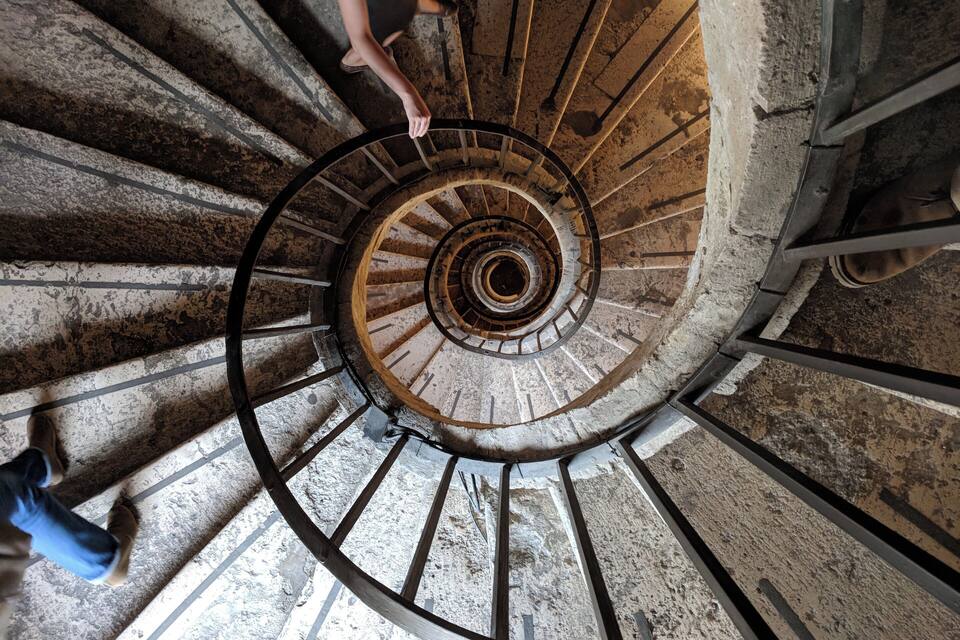 A spiral staircase with a person descending.