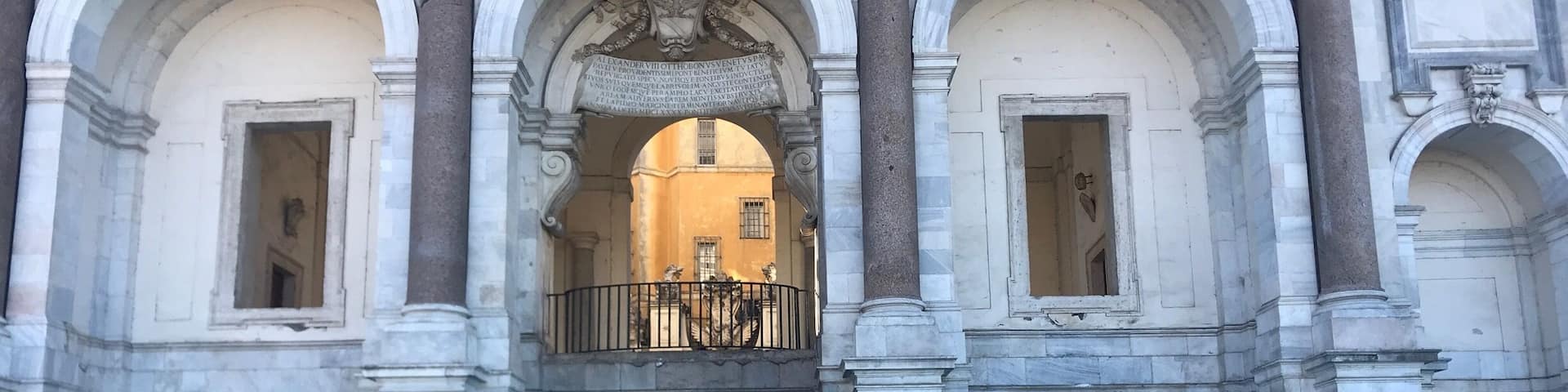 A historic building with arched windows and a fountain in front.
