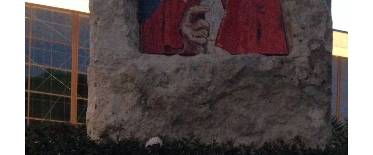 A stone monument with a portrait of a person in a red robe.