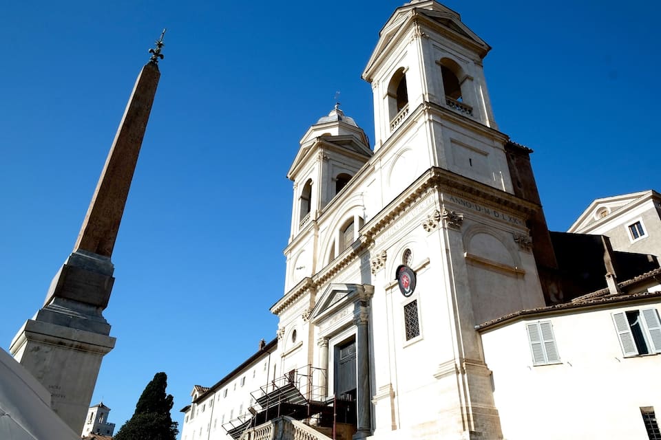 A historic church with a tall bell tower and a prominent obelisk.