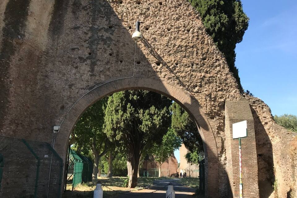 Un ancien pont de pierre, doté d’une grande arche, entouré d’arbres et surplombant un ciel bleu clair.