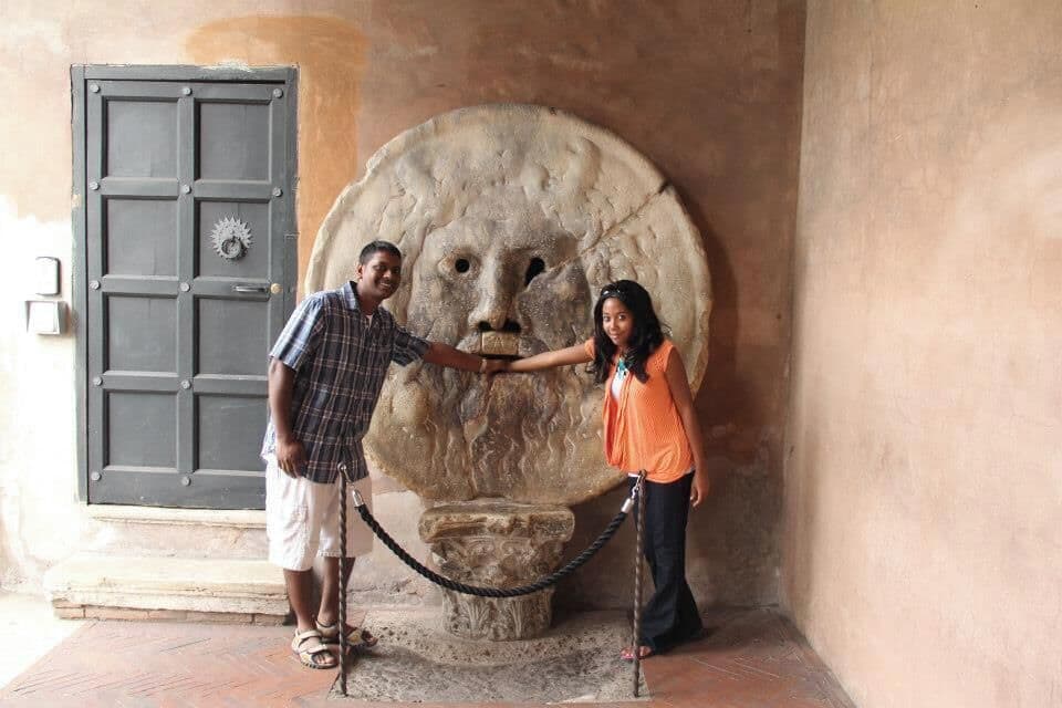 A stone sculpture of a lion's face, a door, and a rope barrier.