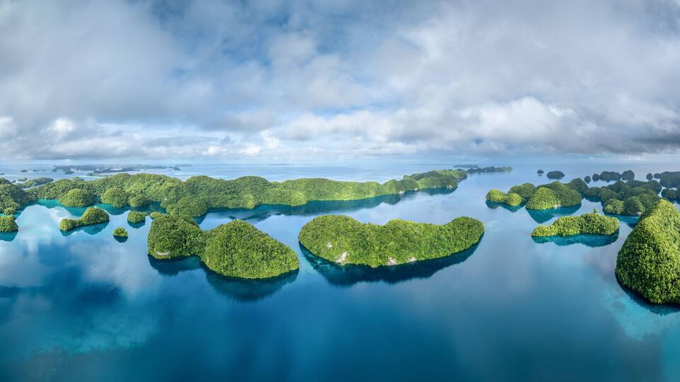 An aerial view of a chain of lush green islands surrounded by clear blue waters.