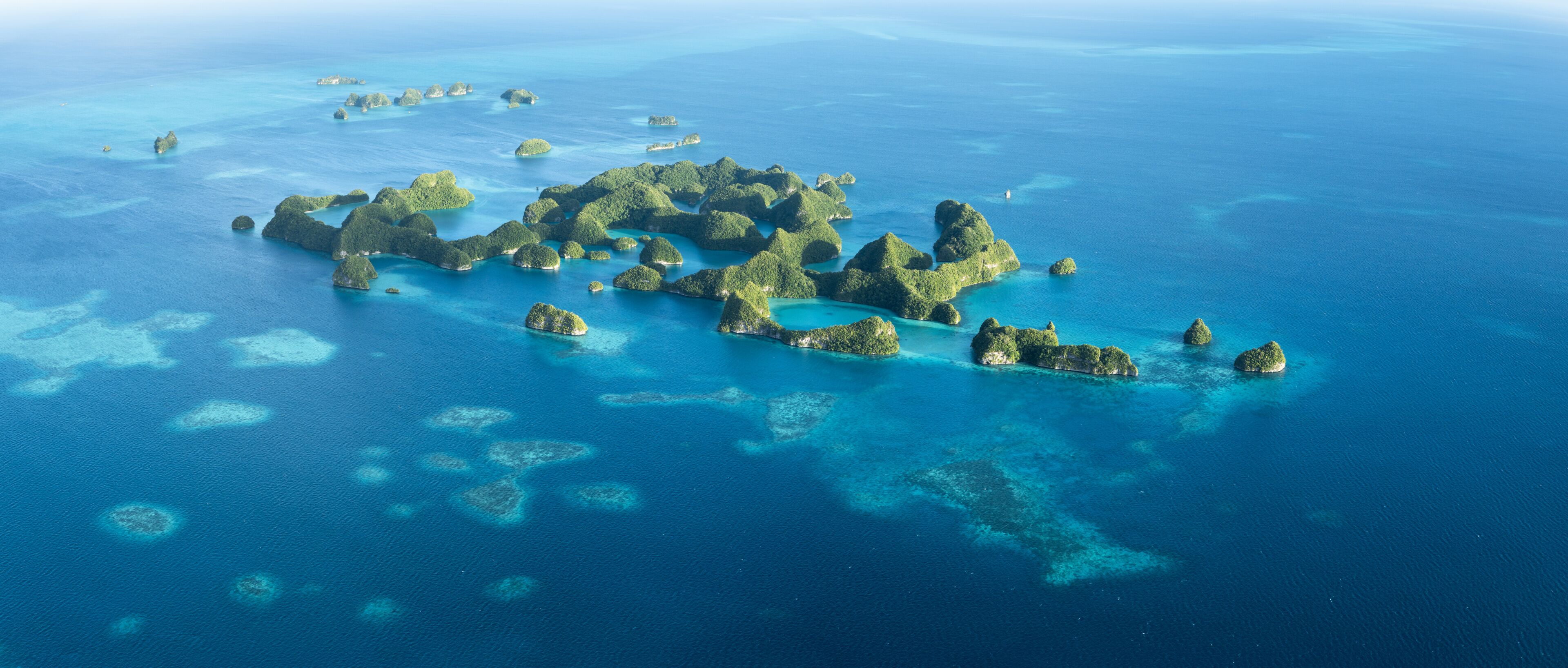 An aerial view of a cluster of islands with clear blue waters and coral reefs.