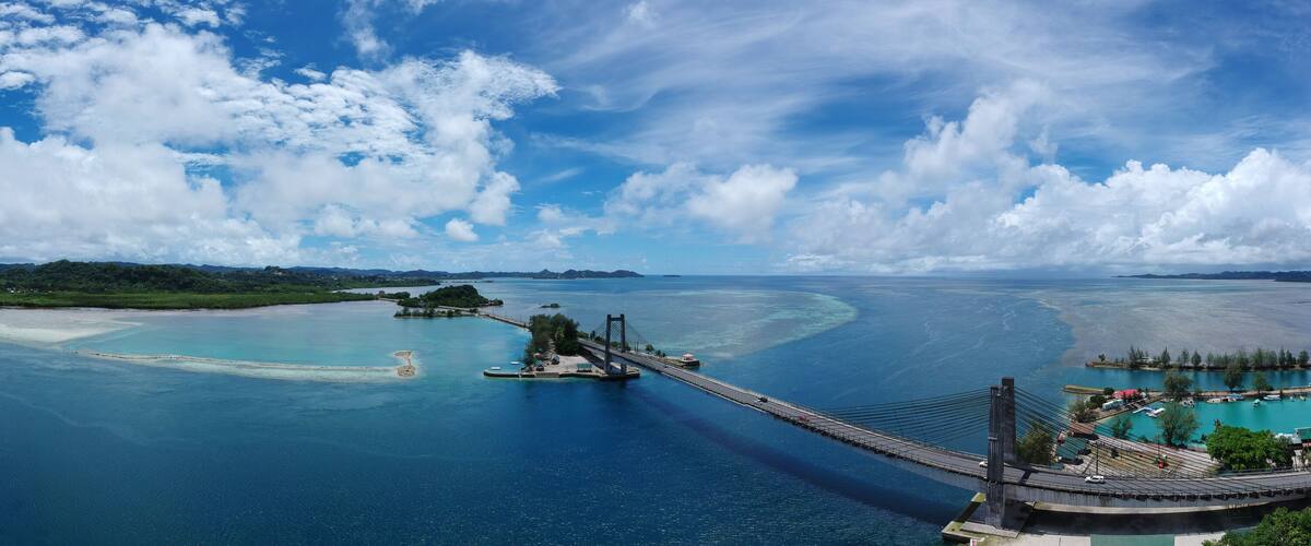 A coastal landscape with a bridge, clear blue waters, and islands.