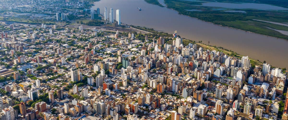 A densely populated city with a river running through it, a bridge, and high-rise buildings.