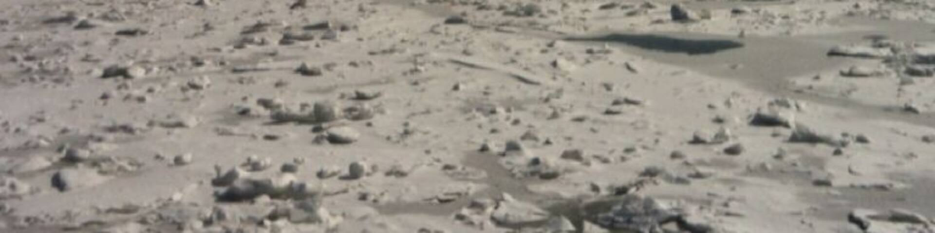 A bridge over a frozen river with scattered ice chunks.