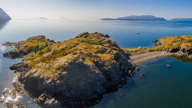 A calm lake with rocky outcrops and distant mountains.