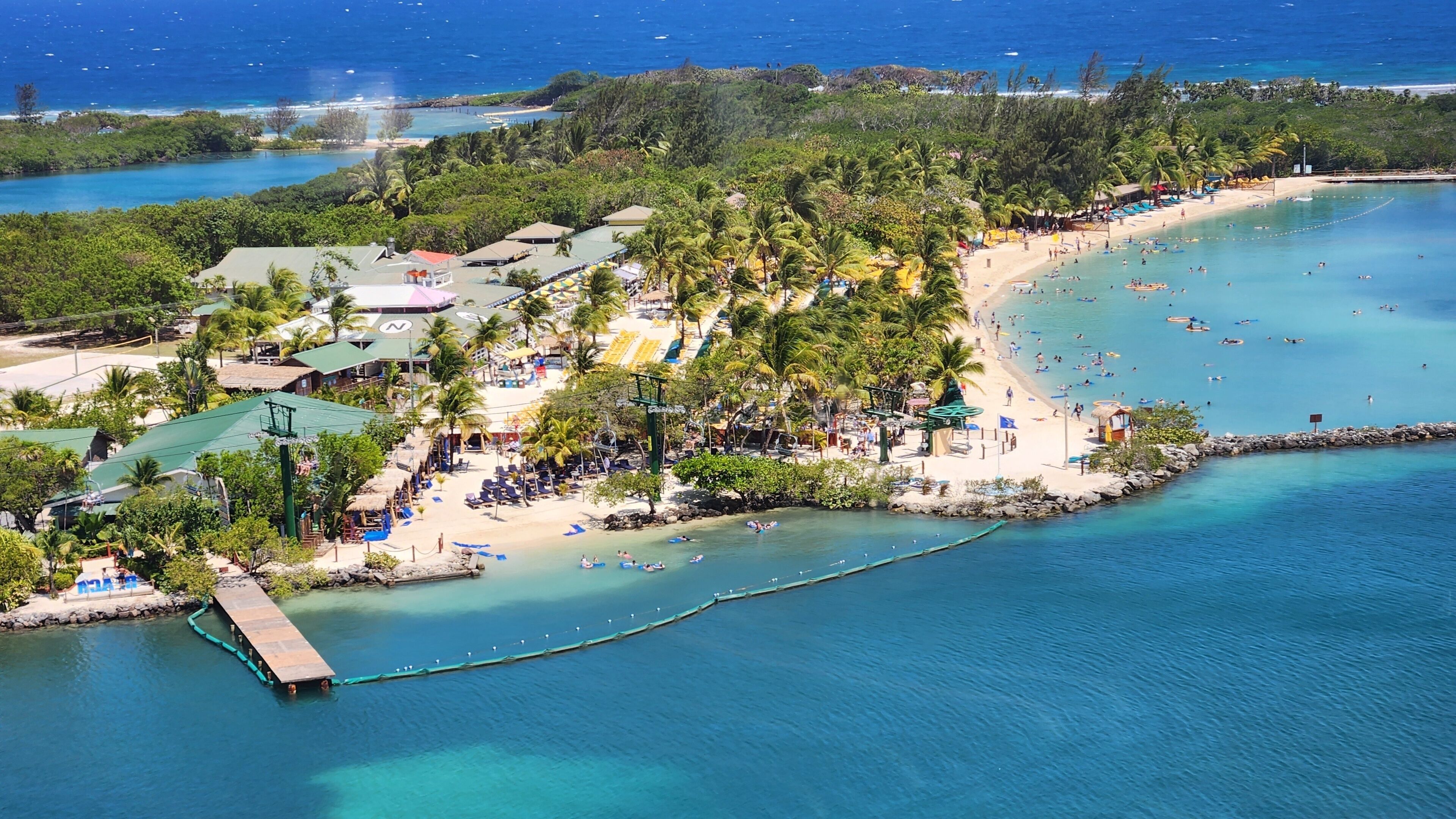 A tropical beach resort with palm trees, a sandy beach, and clear blue waters.