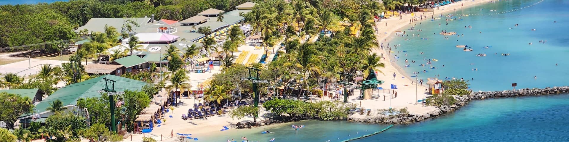 A tropical beach resort with palm trees, a sandy beach, and clear blue waters.