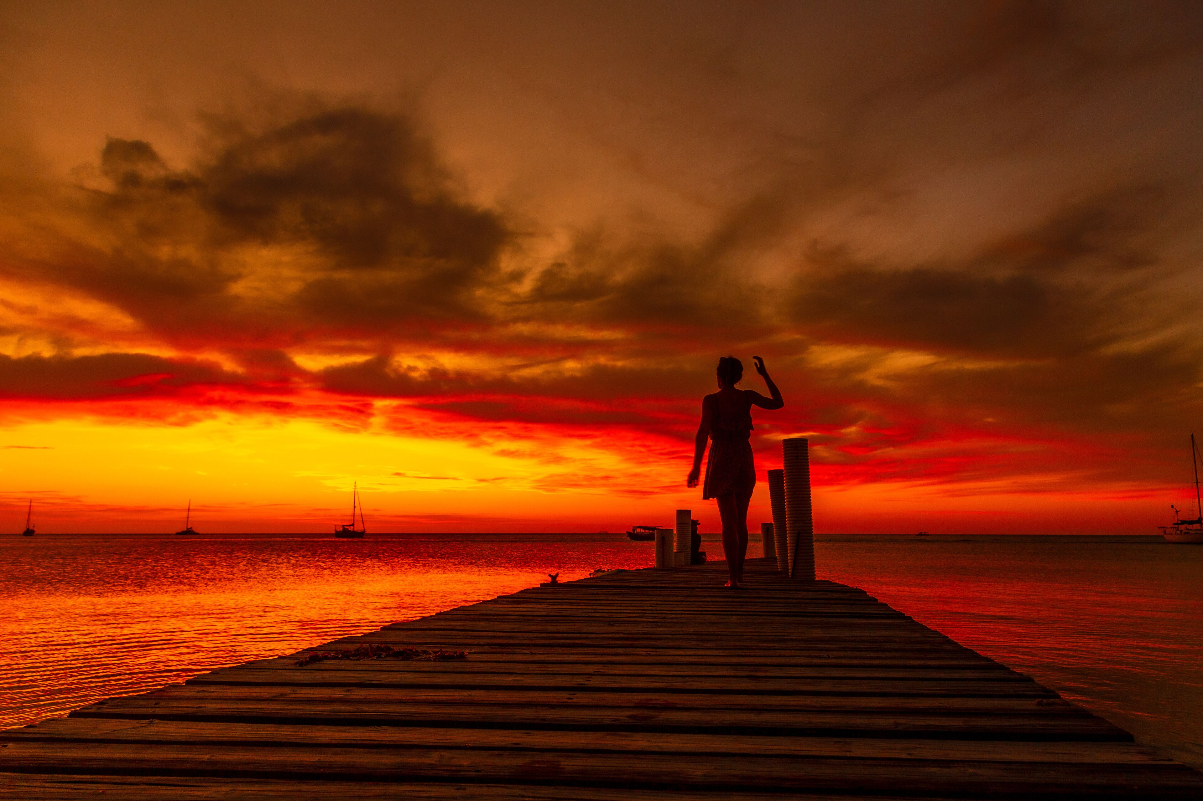 A young woman walking towards the Caribbean Sea at sunset on West End beach in Roatan