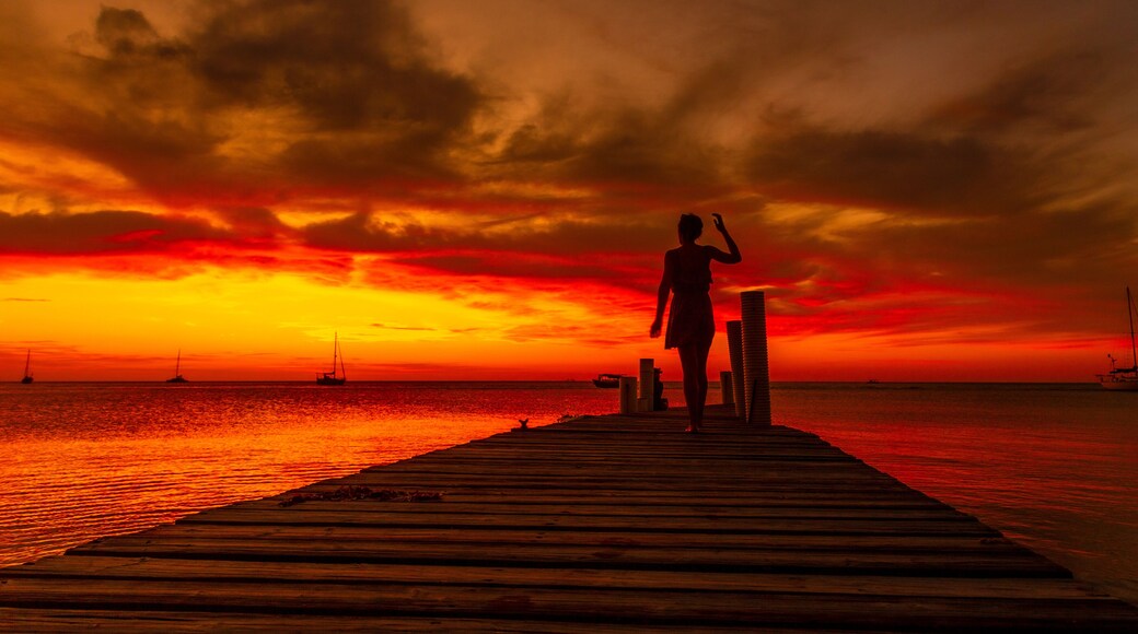 A young woman walking towards the Caribbean Sea at sunset on West End beach in Roatan