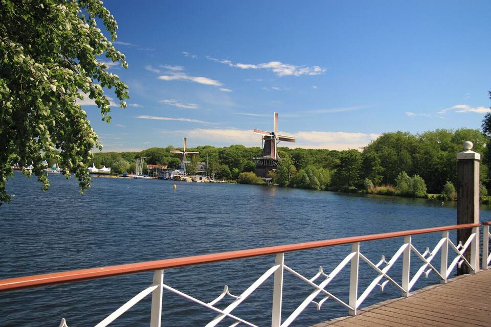A river with windmills and a wooden dock.