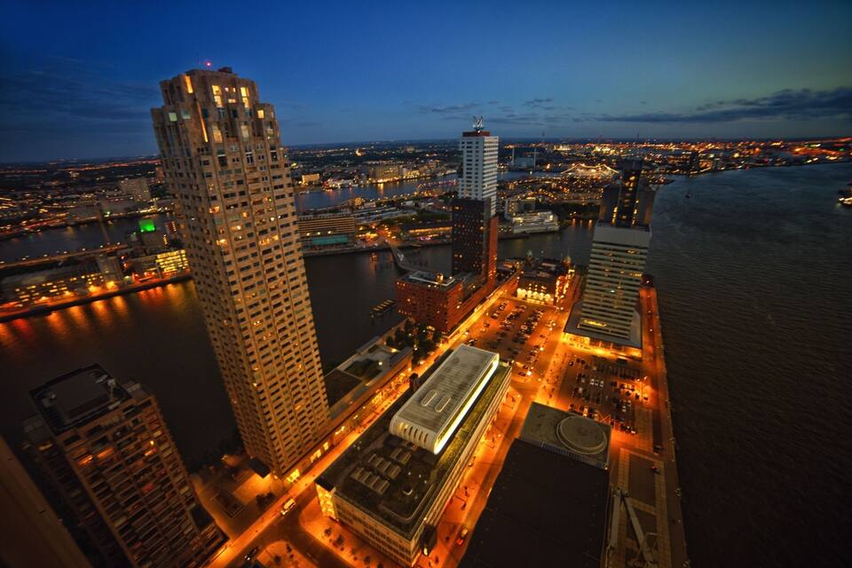 An aerial view of a cityscape at dusk with prominent buildings, a river, and a bridge.