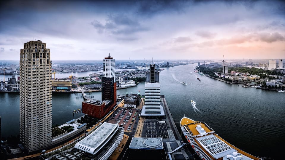 Stadsgezicht met een rivier, hoge gebouwen en een brug.