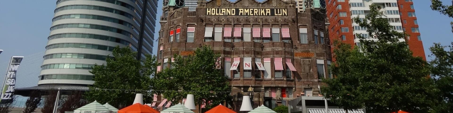 A historic building with a clock tower and the name "Hollanda Amerika LJN" on its facade.