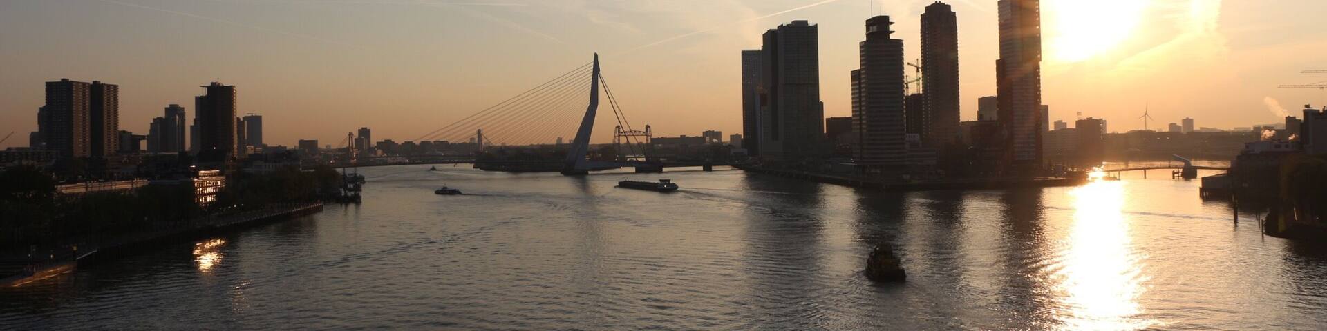 A sunset over a city skyline with a bridge and water.