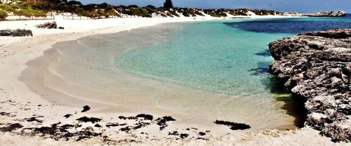 Pinky Beach is on Rottnest Island, 18 kilometres off the coast of Western Australia near Fremantle and Perth.
Rottnest, or “Rotto” as the locals say, is a premier island getaway with over 60 picturesque beaches and bays. 
Pinky beneath is below the Bathurst Point Lighthouse, just a short walk from the Thompson Bay settlement. 
You can stay overnight on Rotto in a range of accommodations, or simply catch the Rottnest Ferry over and back from Fremantle for a memorable day trip.